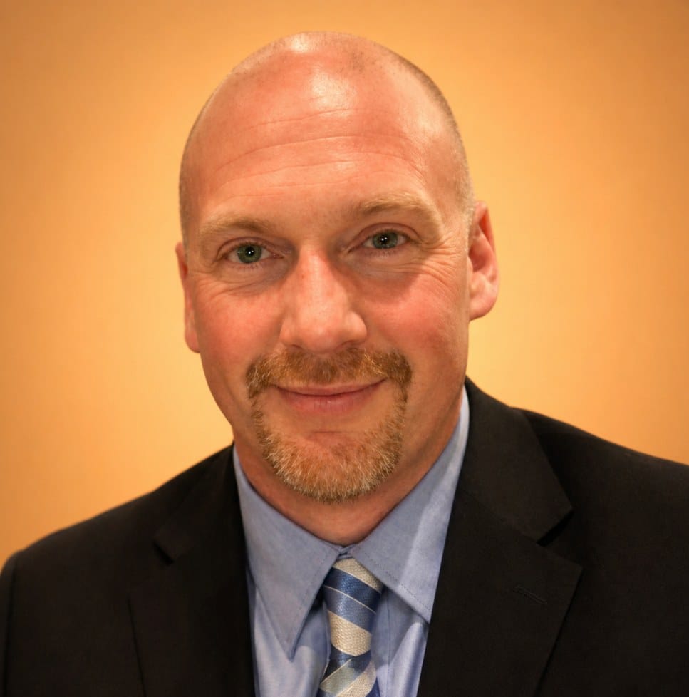 Ryan Penney, owner of Penney Construction, in a dark suit and striped tie